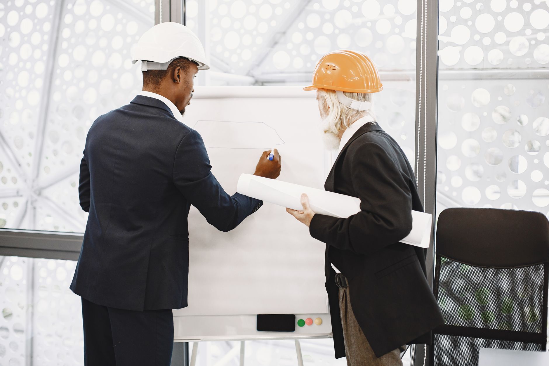 A services team and a manufacturing operator reviewing a documented process together at a whiteboard
