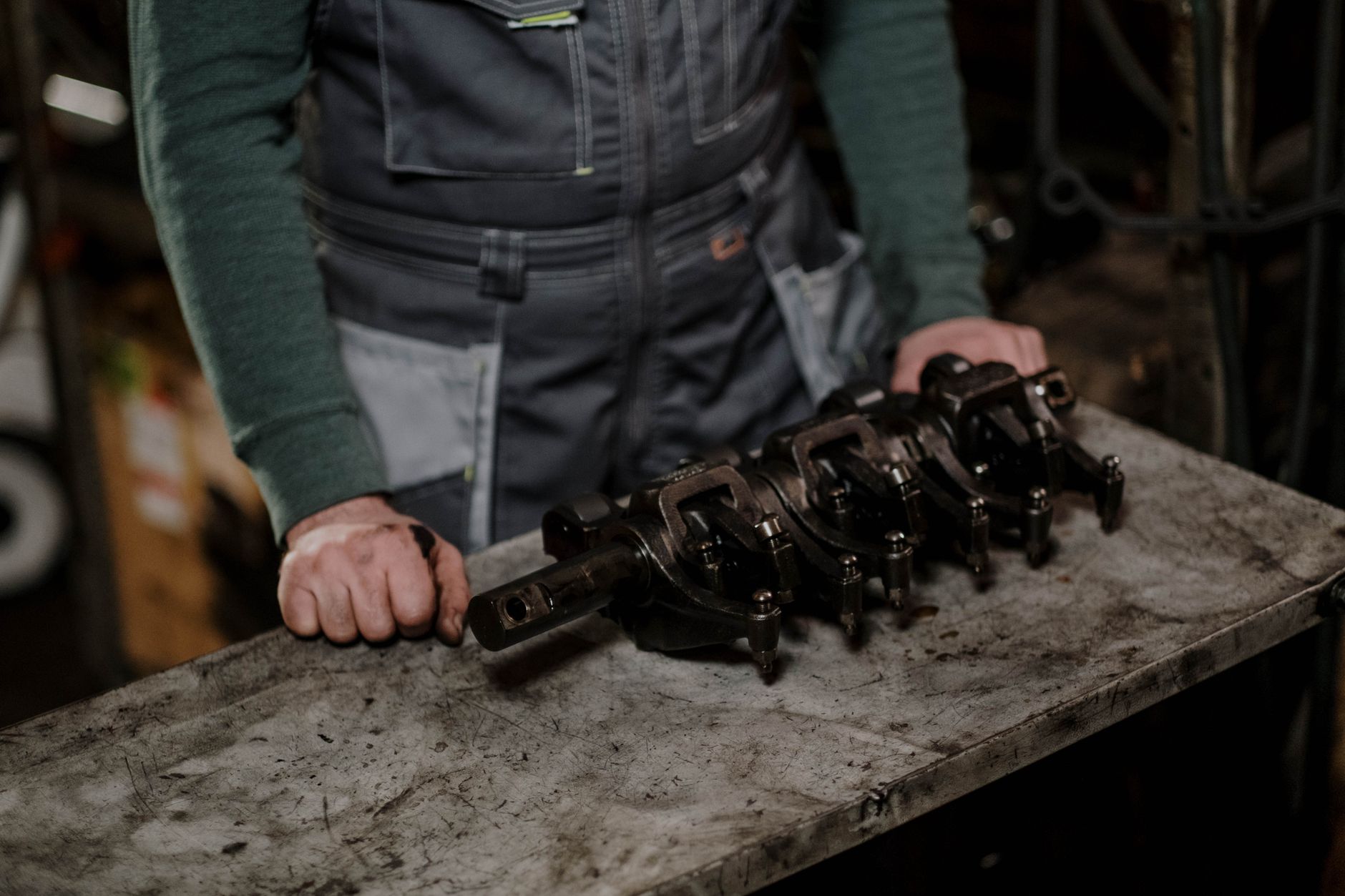 A worker holding a multi-part assembled component on a workshop bench